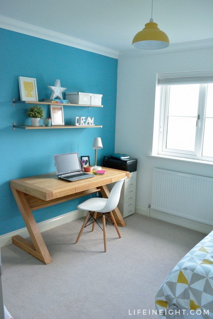 a desk with a laptop on top of it in front of a blue painted wall