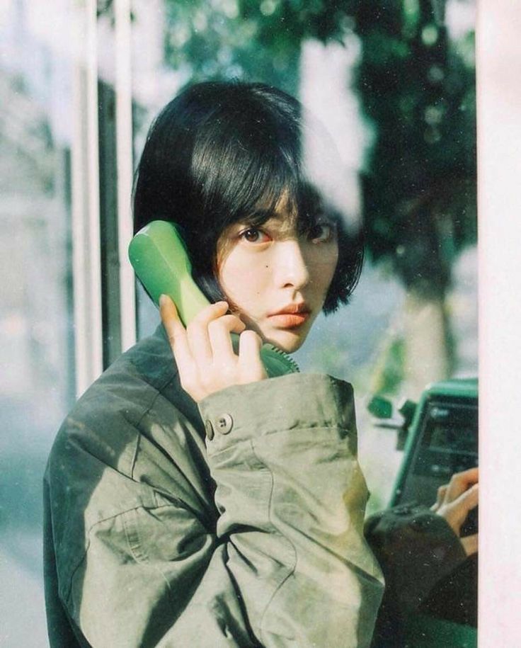 a woman talking on a cell phone while holding a green object up to her ear