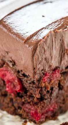 a close up of a piece of cake on a plate with chocolate frosting and strawberries