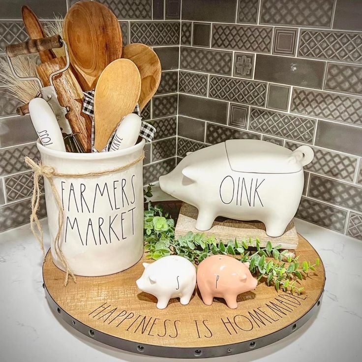 two pig figurines sitting on top of a cutting board with utensils