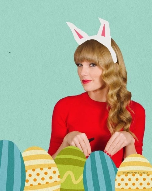 a woman in a red shirt and bunny ears holding an easter egg with painted eggs around her