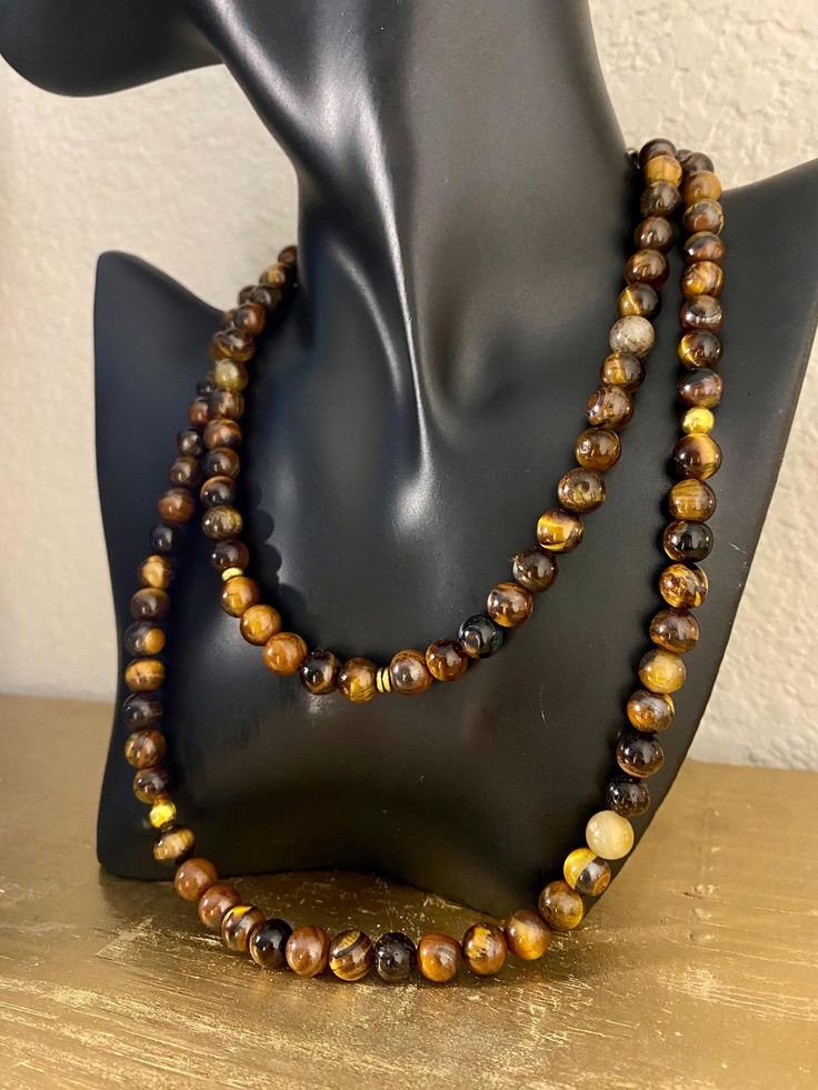 A lot of style and a lot more meaningful. This one is for him or her. ✨ Made with high quality Tigers Eye gemstones, with a few added gold accent beads.  Tigers Eye is a beautiful and powerful stone and symbol of focus and clarity. It's known to help enhance self confidence and self awareness, which can help strengthen Will power and integrity.  One necklace per order Comes in two Sizes Short: Adjustable from 14in to 16in Long: 24' Spiritual Brown Agate Beads, Spiritual Amber Crystal Necklaces With Round Beads, Brown Healing Amulet Jewelry, Brown Round Jewelry For Healing, Holistic Brown Necklace With Natural Stones, Brown Amulet Style Jewelry With Natural Stones, Brown Amulet Jewelry With Natural Stones, Spiritual Amber Beaded Necklaces With Natural Stones, Brown Natural Stones Amulet Jewelry