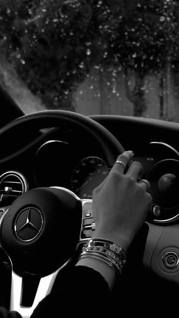 a person driving a car in the rain with their hands on the steering wheel and dashboard