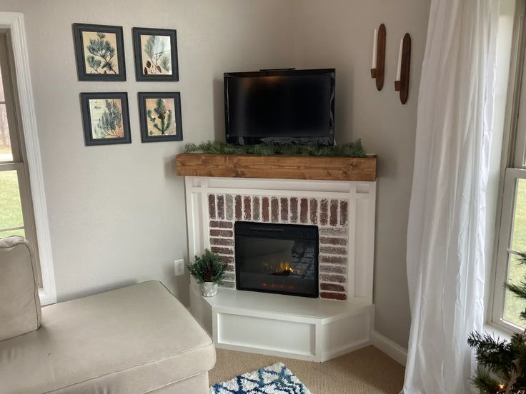 a living room with a fireplace, television and pictures on the wall above it's mantle