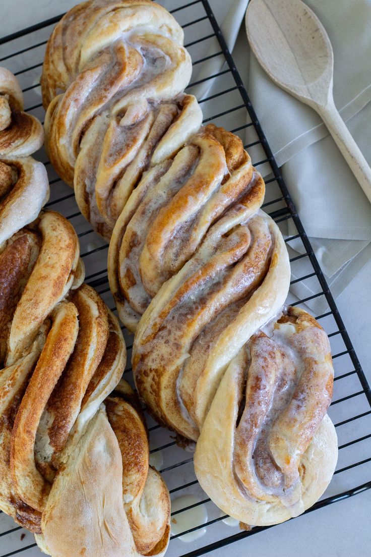 several cinnamon rolls sitting on top of a cooling rack next to a spoon and fork