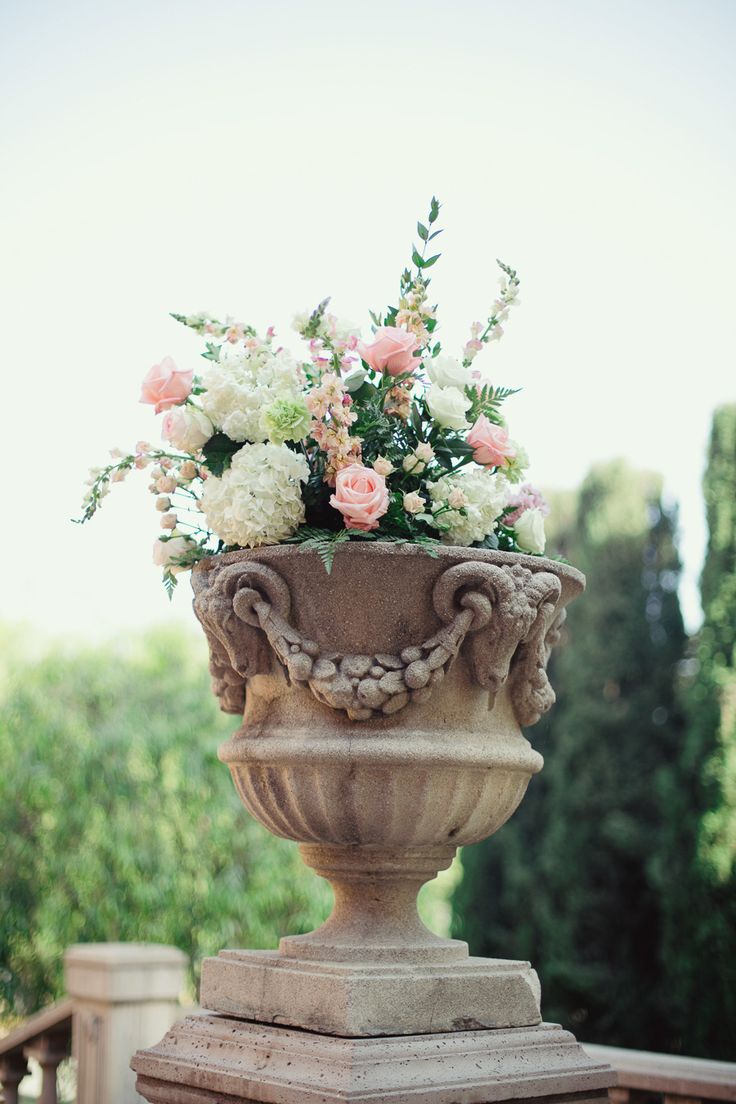 a vase filled with flowers sitting on top of a wooden table next to a fence