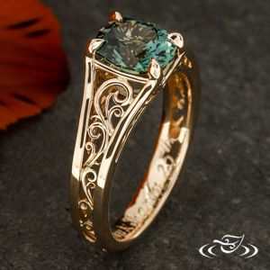 a gold ring with a green stone in the center and filigrees on it