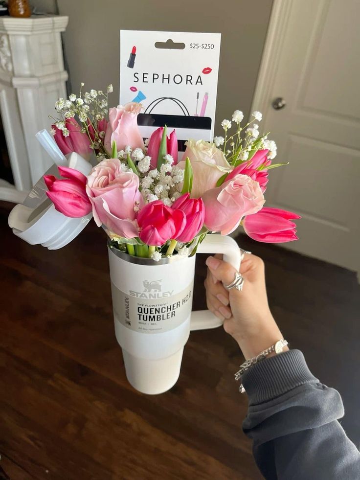 a person holding a bouquet of flowers in a coffee cup with the name sephora on it