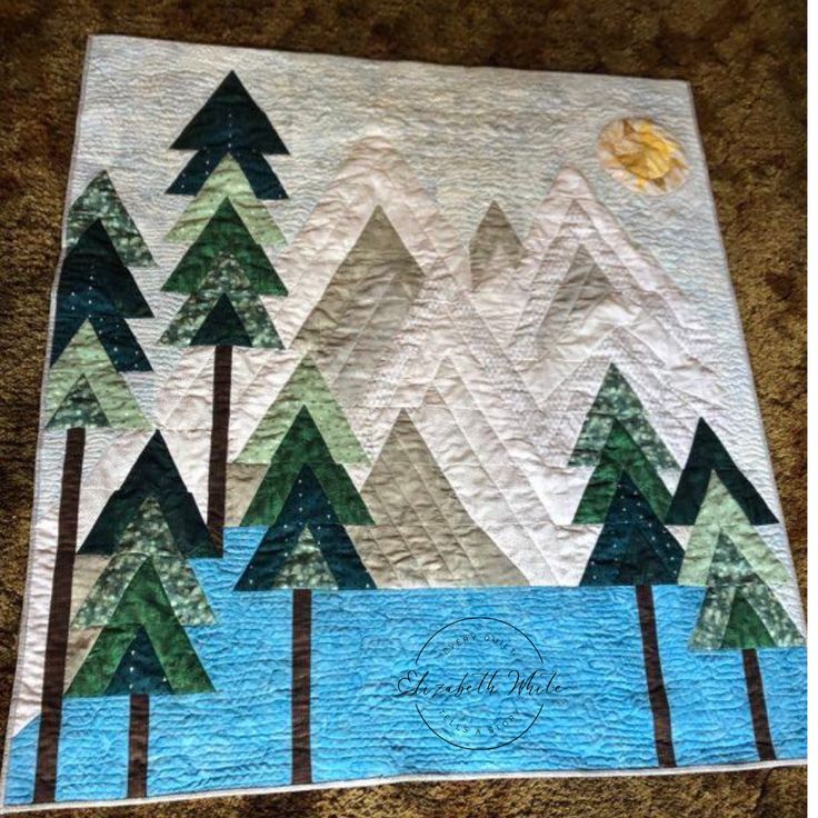 a quilted wall hanging with trees on it