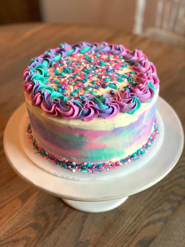 a colorful cake with sprinkles and frosting sitting on a white plate