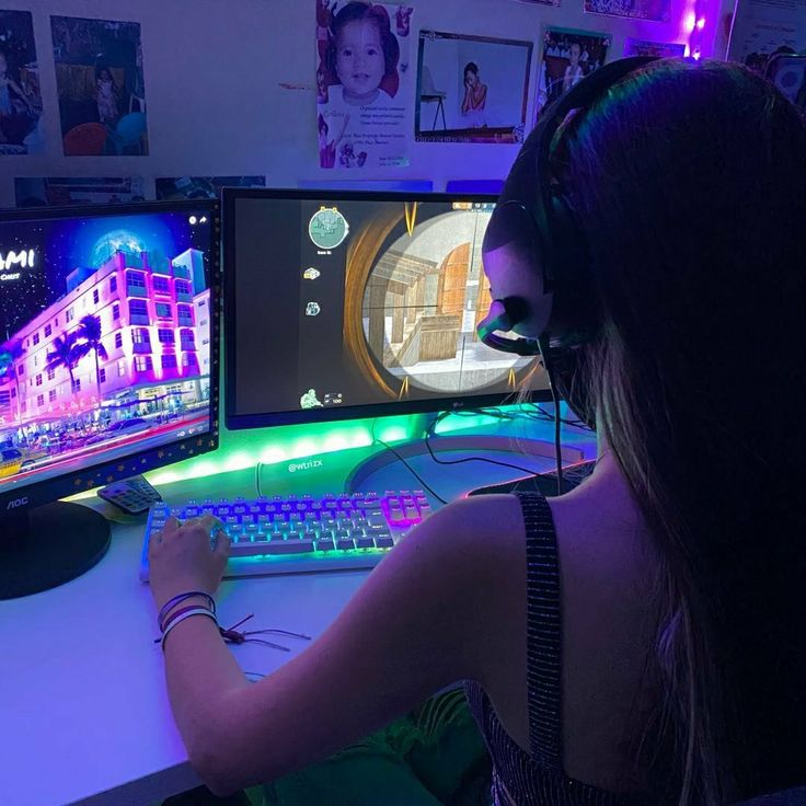 a woman sitting in front of a computer monitor with headphones on and looking at the screen