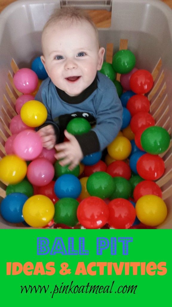 a young boy sitting in a ball pit with lots of colorful balls on the ground