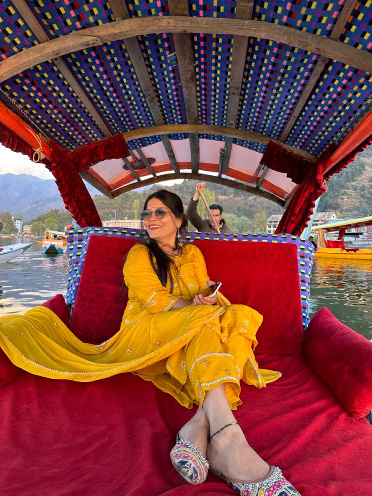 a woman sitting on top of a red couch in front of a body of water