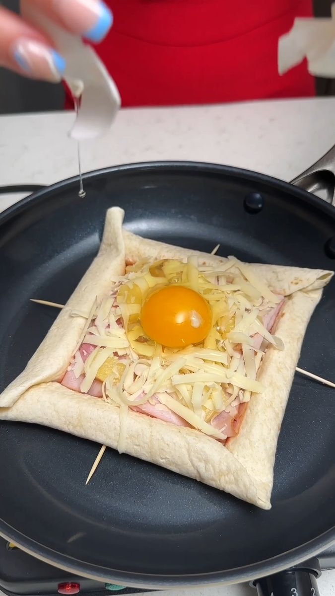 an egg is placed on top of a pizza in a pan with toothpicks