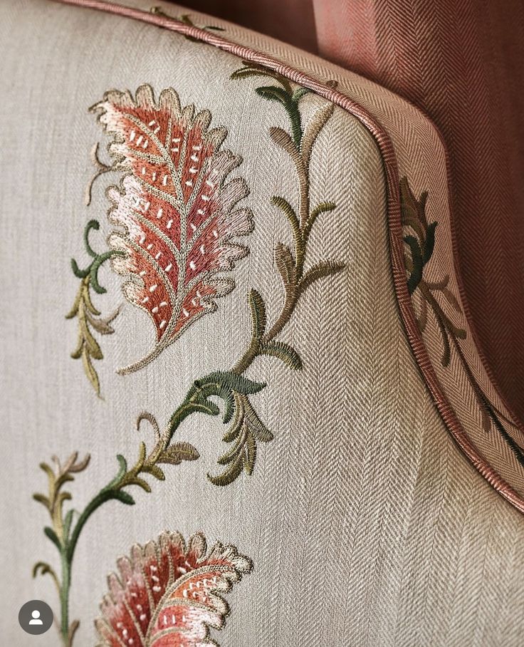 the back of an upholstered chair with embroidered flowers on it