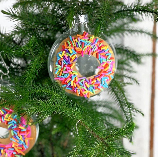 an ornament hanging from a christmas tree decorated with donuts and sprinkles