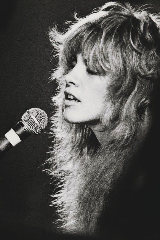 a black and white photo of a woman singing into a microphone