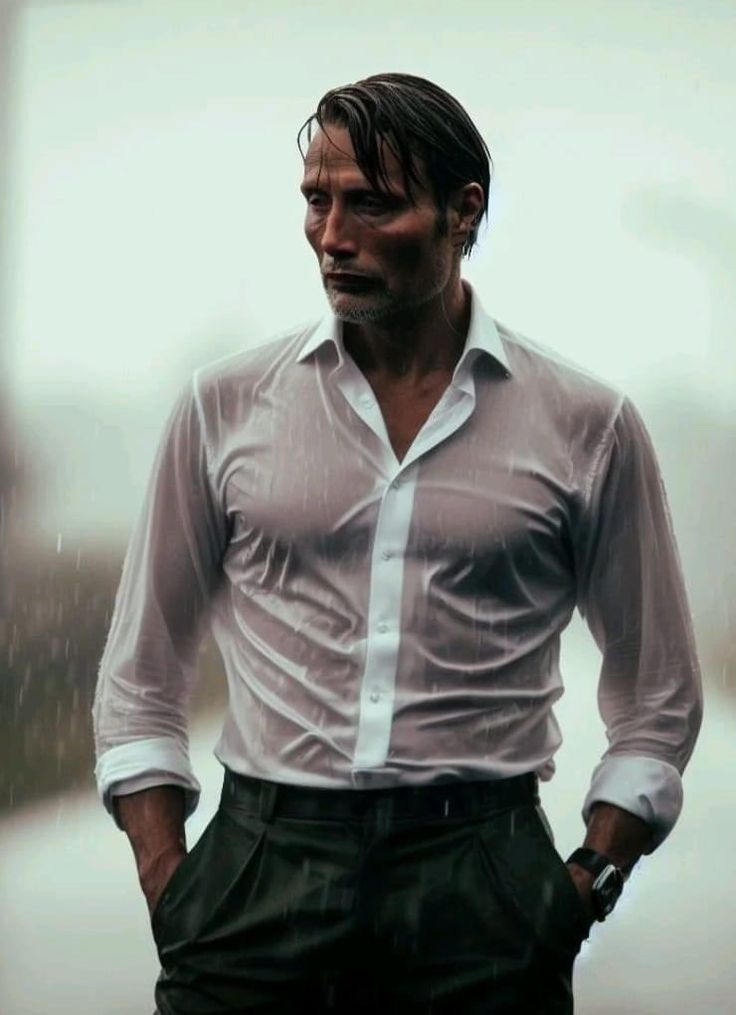 a man standing in the rain with his hands on his hips and wearing a white shirt