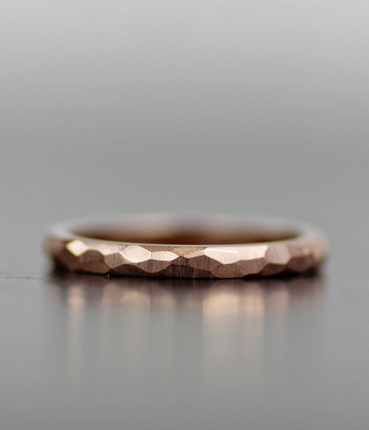 a gold wedding band on top of a gray surface, with the ring in the middle