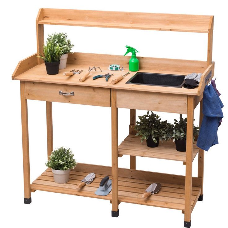 a wooden workbench with plants and tools on it