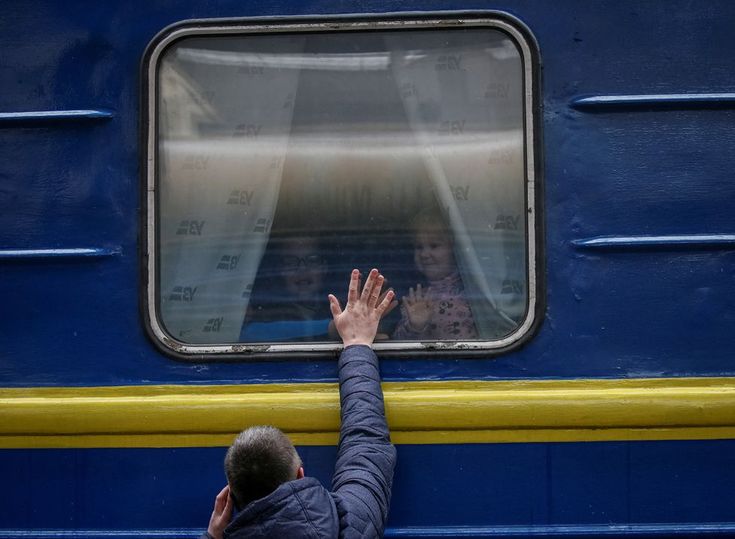 a man is looking out the window of a blue train with his hands in the air