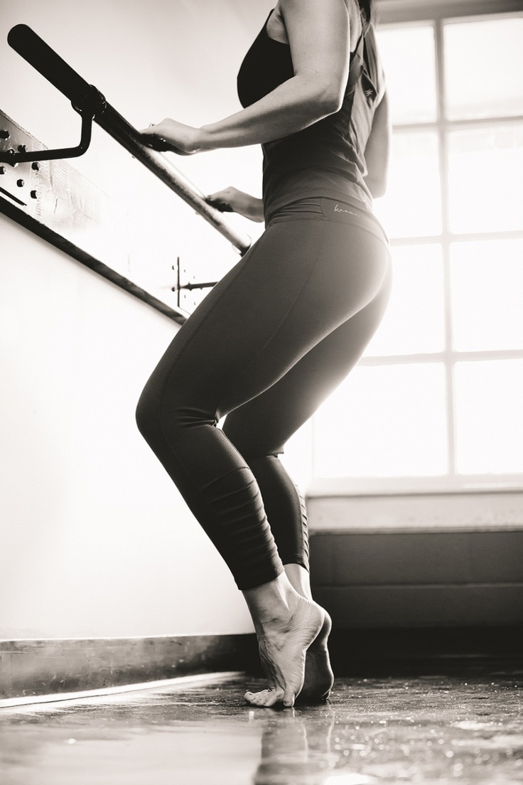 black and white photograph of a woman in tights holding a baseball bat while leaning against a wall