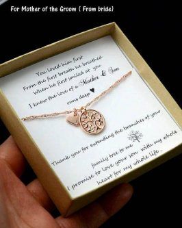 a hand holding a necklace in a box with a message on it that says, for mother of the groom from bride