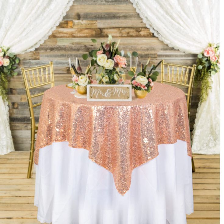 the table is decorated with gold sequins and pink flowers, along with two chairs