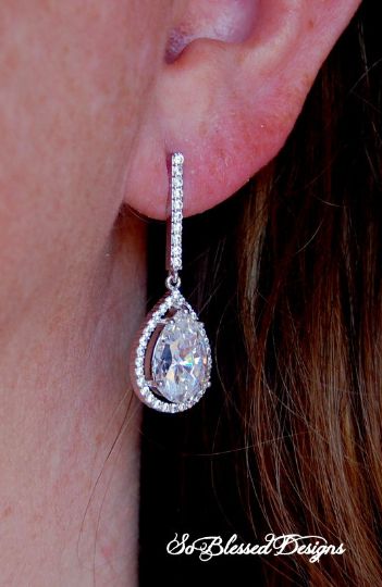 a woman's ear is shown with a pair of earrings in the shape of a tear