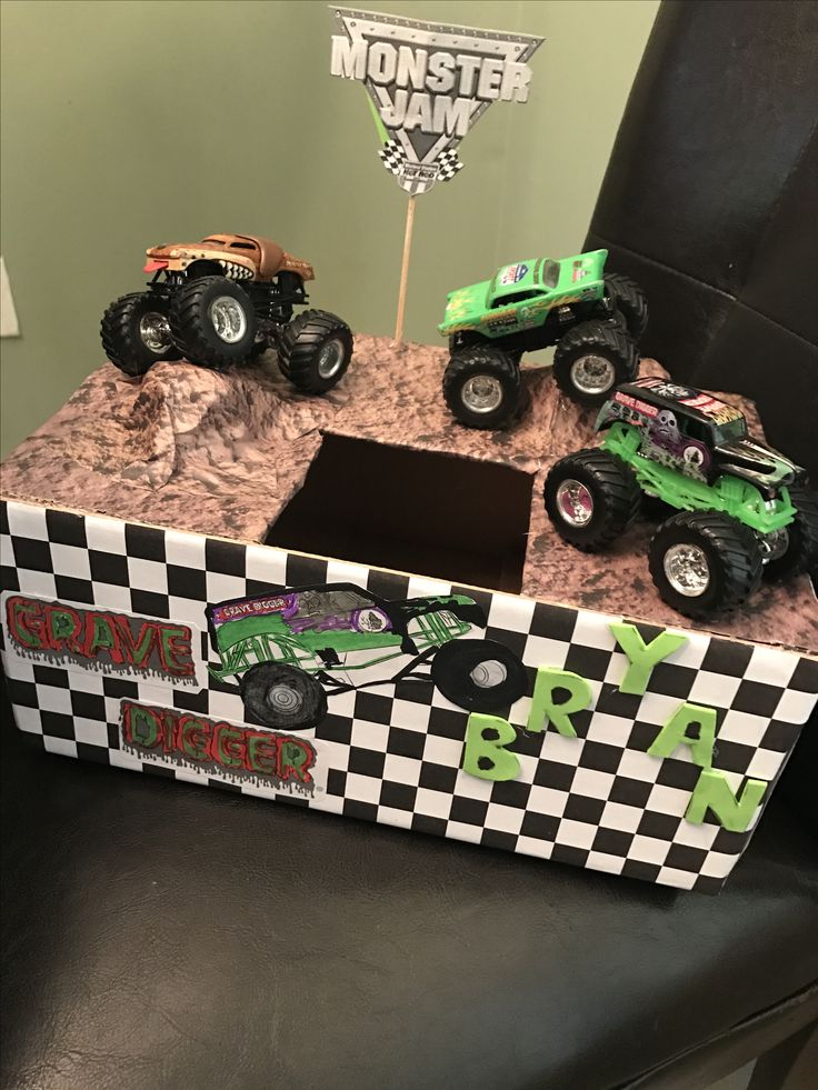 three monster trucks are sitting on top of a box that is decorated with black and white checkered paper