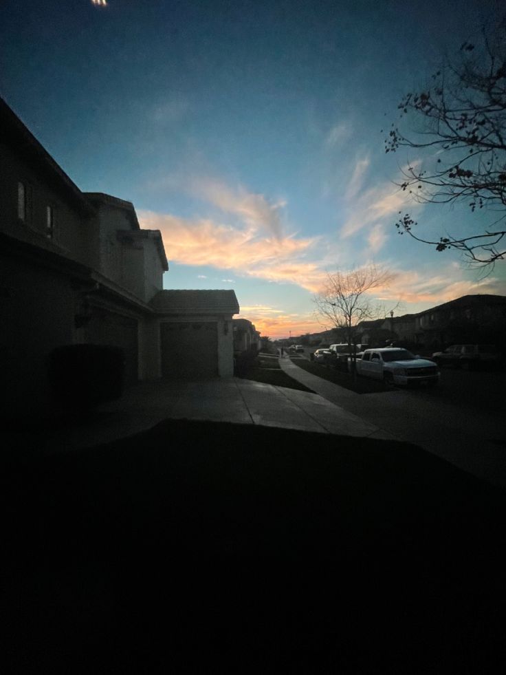 the sun is setting over some houses and cars