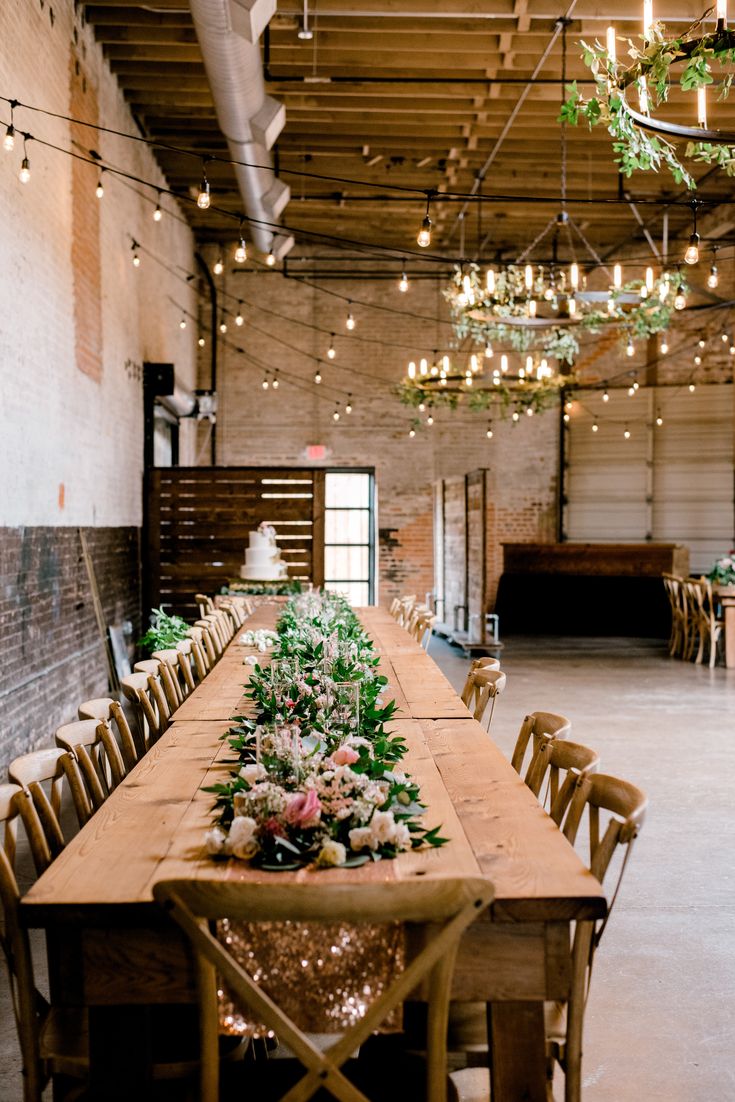 the long table is set with flowers and greenery