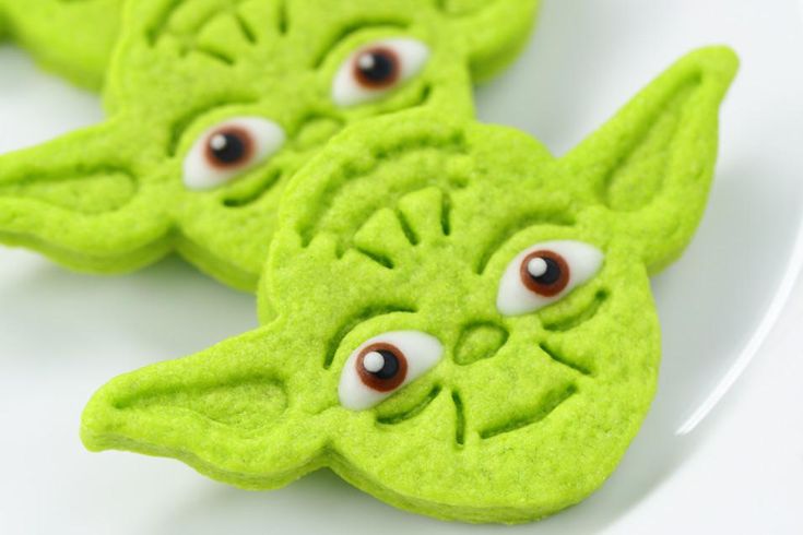 some green cookies with googly eyes are on a plate