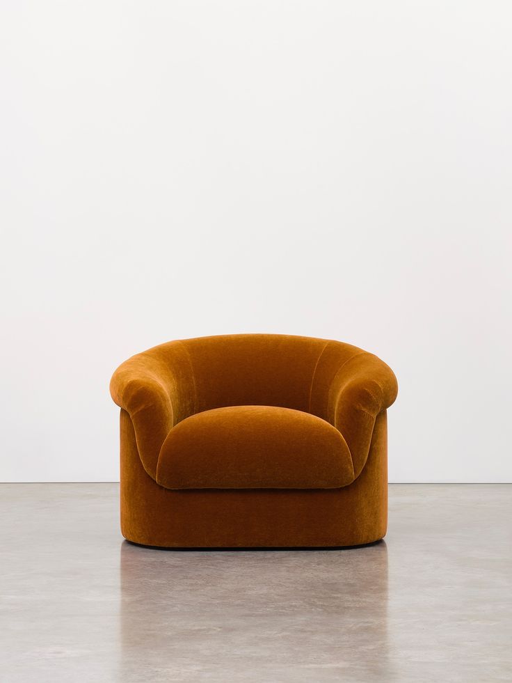 an orange chair sitting on top of a cement floor next to a white wall in a room