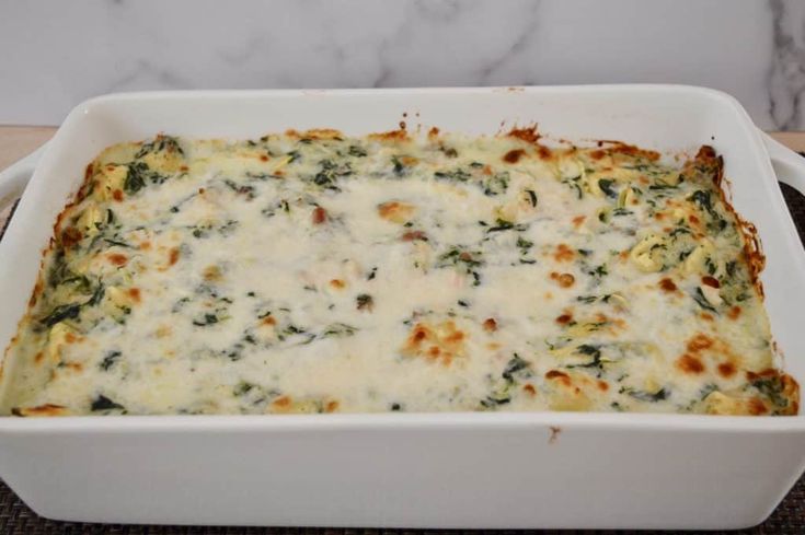 a casserole dish filled with cheese and spinach