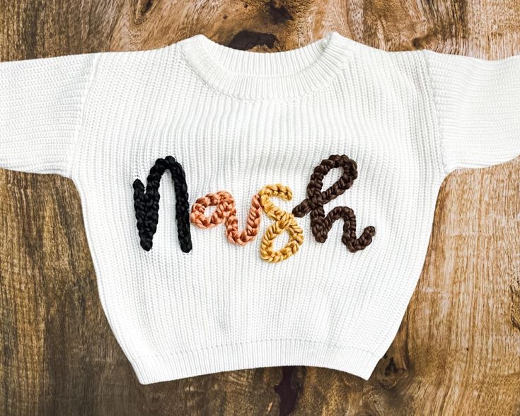 a knitted sweater with the word mom spelled out in black, orange and brown letters