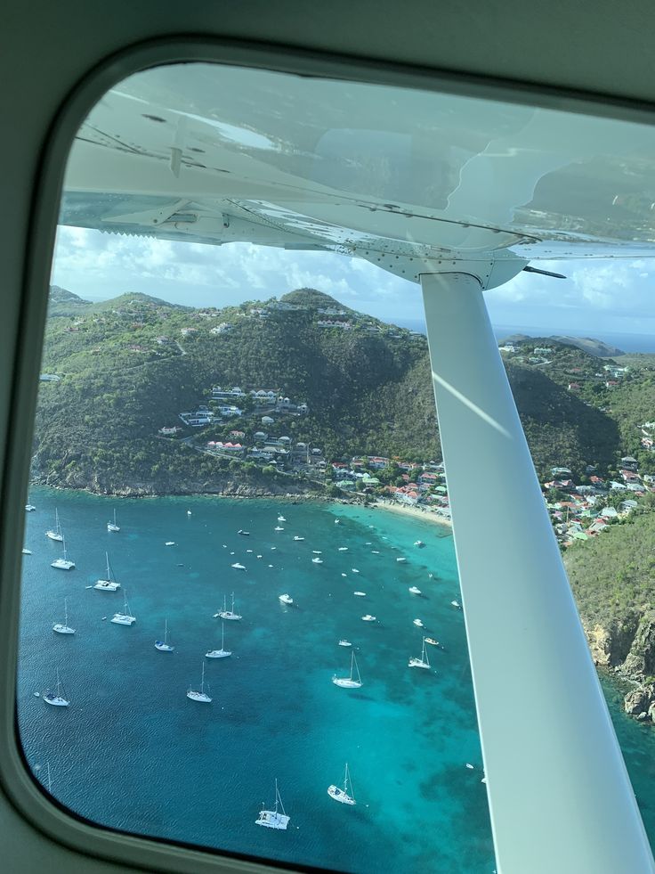 the view out an airplane window shows sailboats in the water