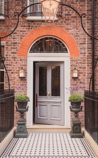 an entrance to a brick building with potted plants on the steps and wrought iron railings