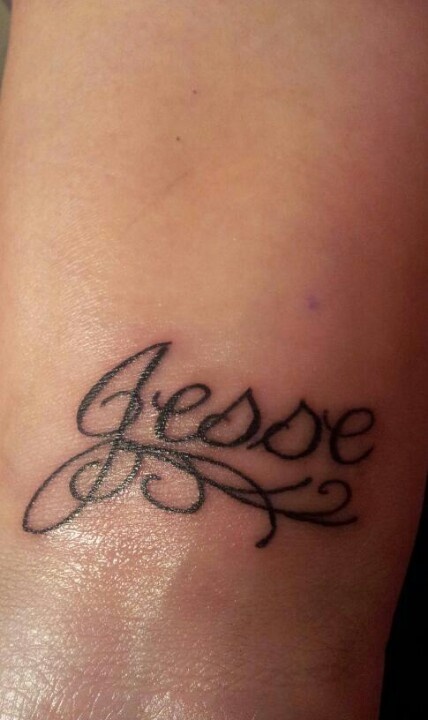 a small tattoo on the ankle that says jesey in cursive font,