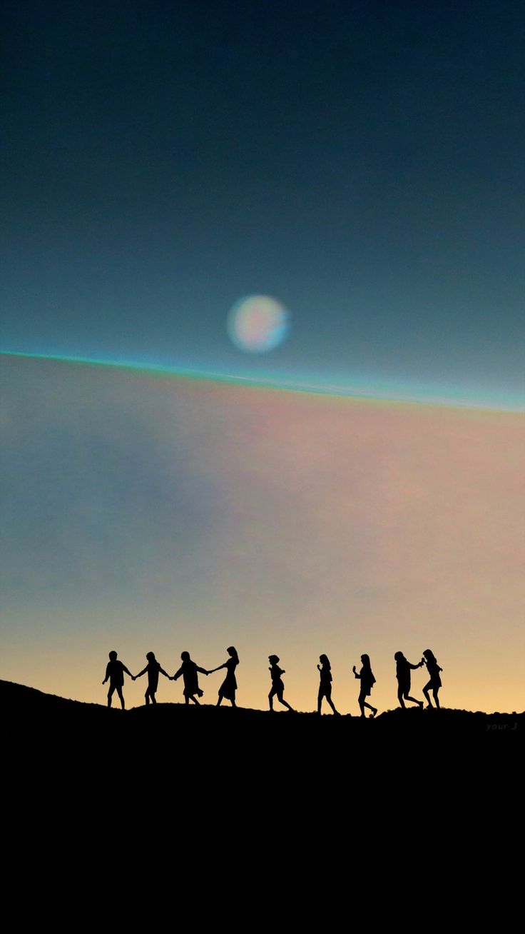 a group of people walking across a field under a sky with a rainbow in the background