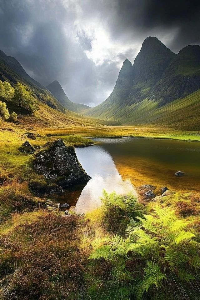 a lake in the middle of a mountain range surrounded by green grass and tall mountains