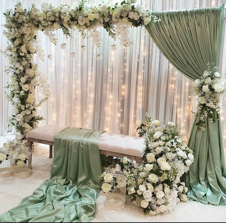 a white and green wedding ceremony setup with flowers on the table, draped drapes