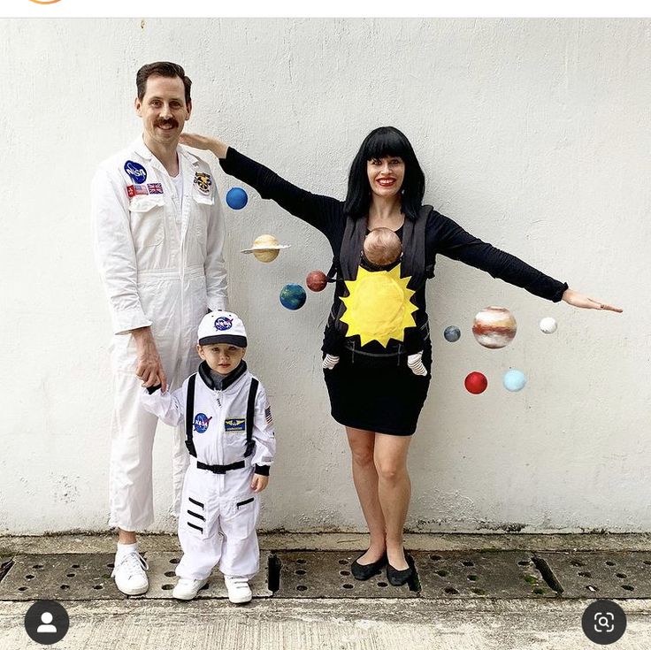 a man, woman and child are dressed up as outer space characters in front of a white wall