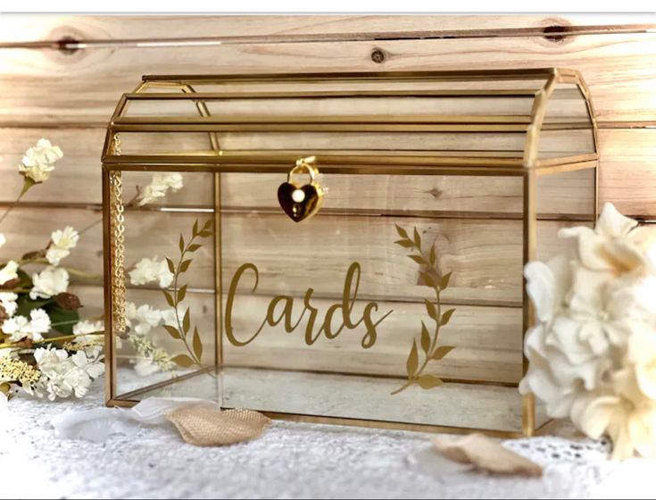 a glass box with the word cards written on it next to flowers and seashells