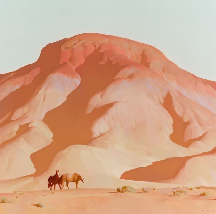 two horses are standing in the desert with a mountain in the backgrouf