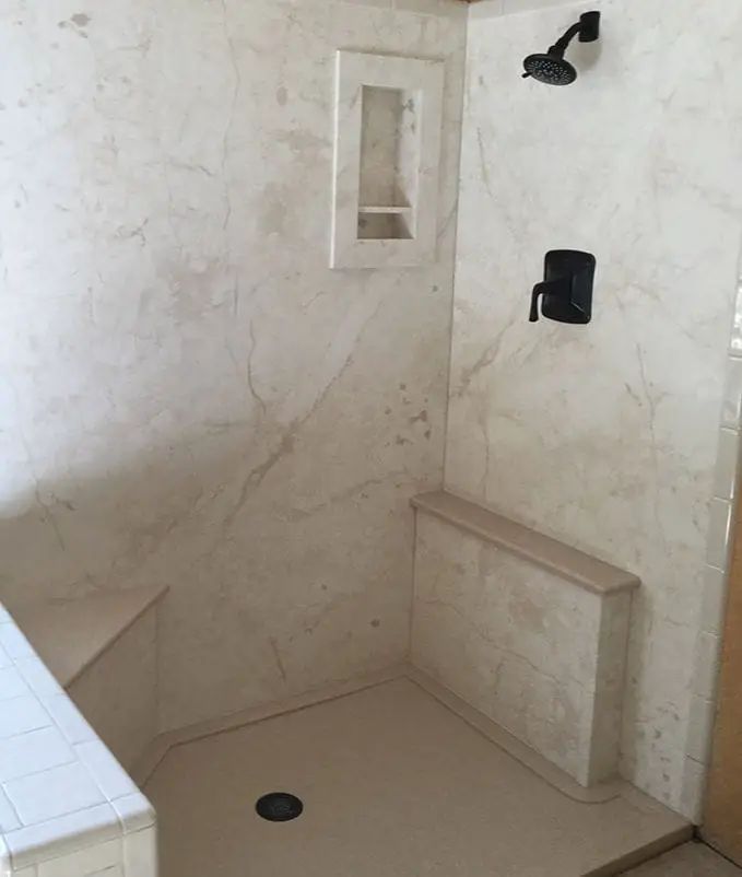 a bathroom with white marble walls and flooring, including a walk in shower area