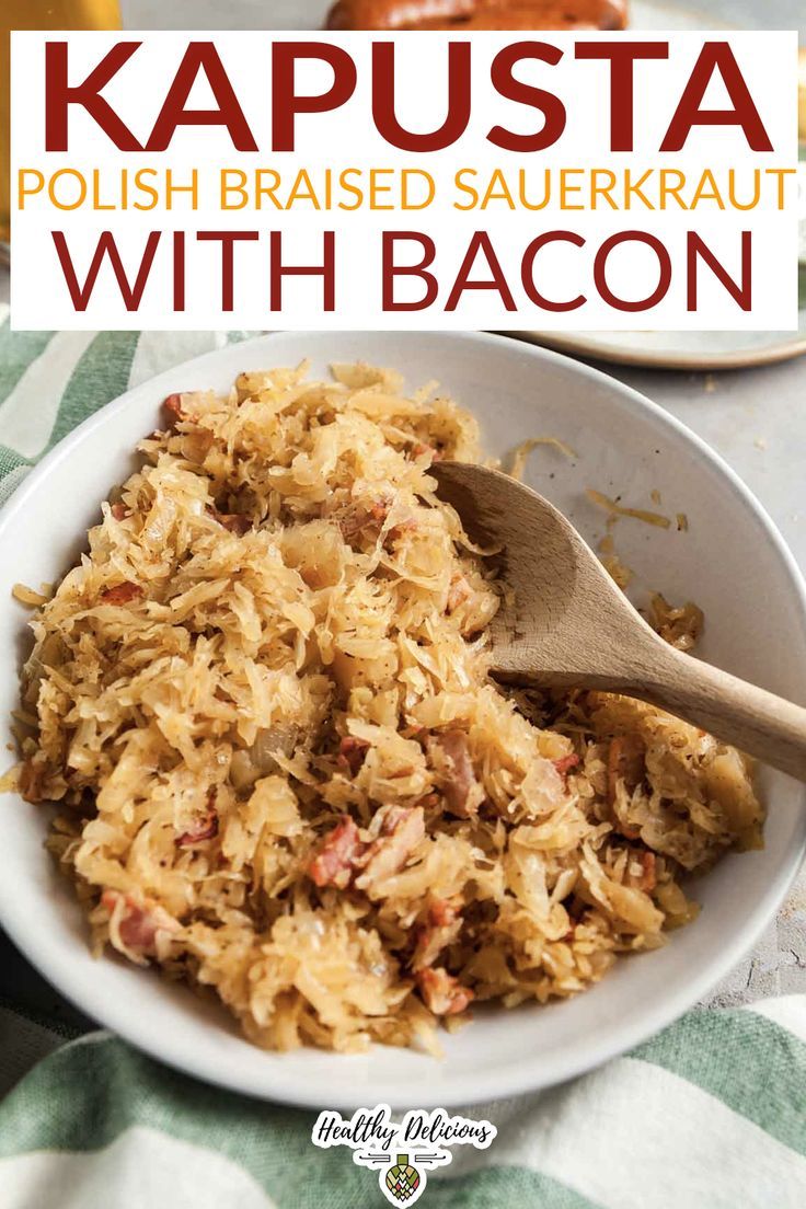 a bowl filled with sauerkraut and topped with bacon next to a wooden spoon