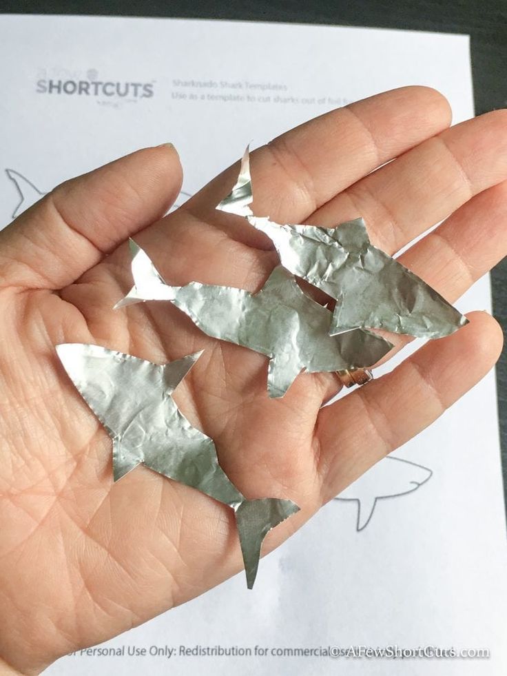 a person is holding some silver origami pieces in their hand and it looks like they are flying