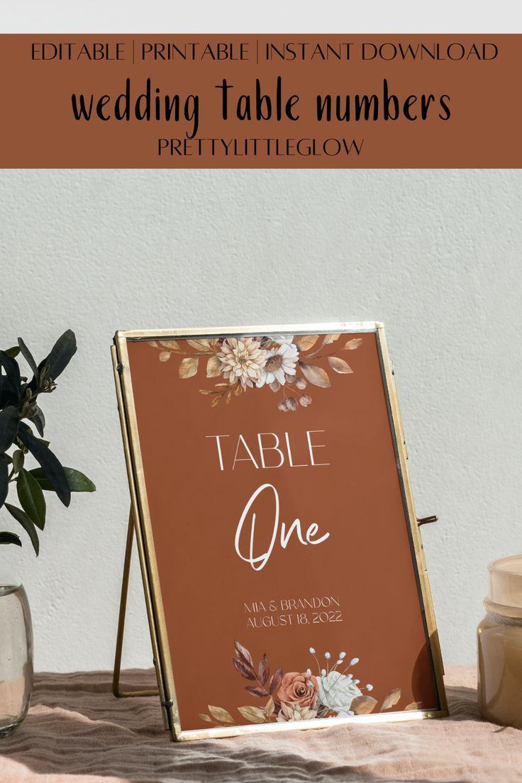 a table number sign sitting on top of a wooden table next to a potted plant