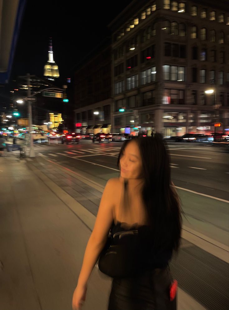 a woman is walking down the street at night with her eyes closed and head turned to the side